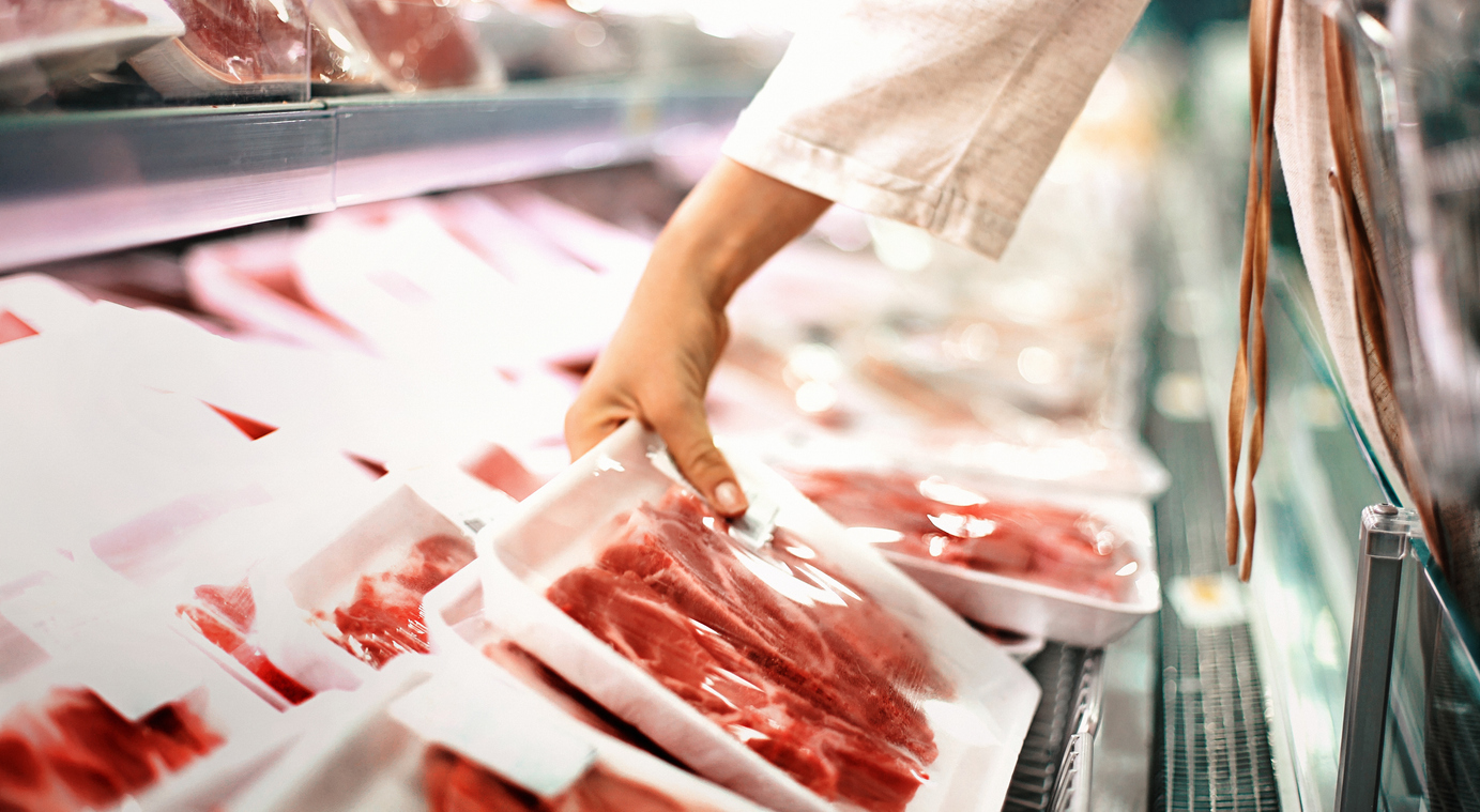 Hand grabbing pack of steaks from cooler area